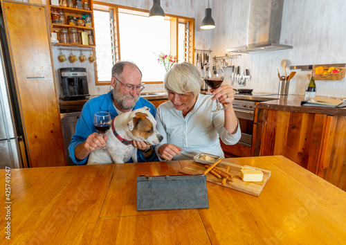 Happy senior couple with dog pet online video calling on tablet family and friends