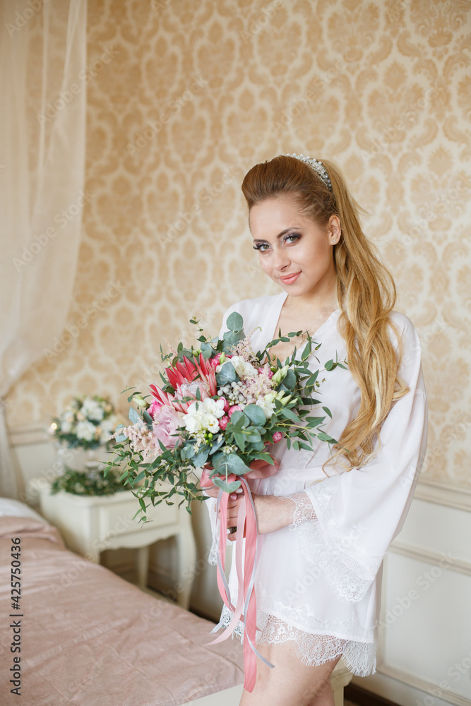 Pretty young Bride with wedding bouquet. Blonde-haired woman with wedding hair-style with a long tail. Boudoir morning of the bride. Pretty young Bride with wedding bouquet. Blonde-haired woman with wedding hair-style with a long tail. Boudoir morning of the bride.