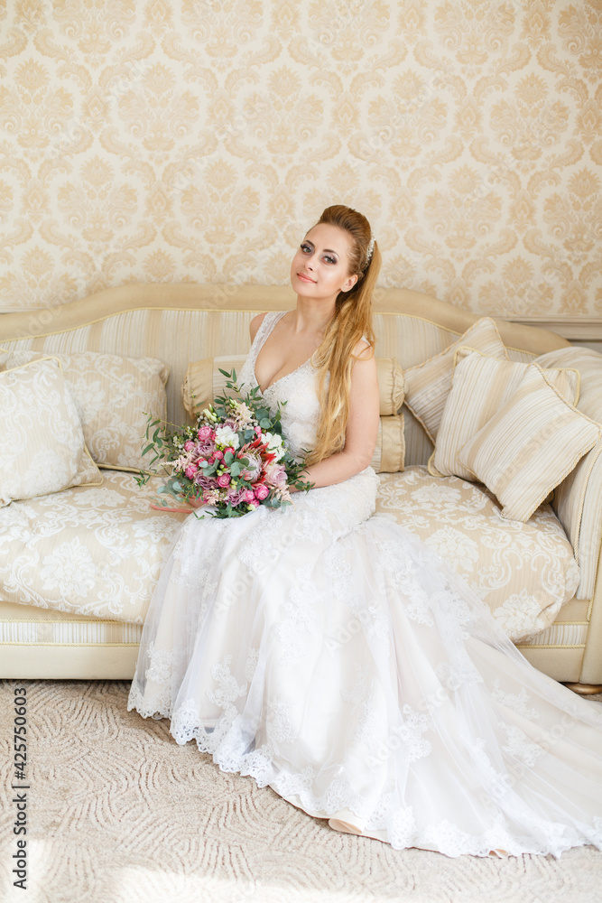 Pretty young Bride. Blonde-haired woman with wedding hair-style with a long tail. Boudoir morning of the bride. Looking to the camera Pretty young Bride. Blonde-haired woman with wedding hair-style with a long tail. Boudoir morning of the bride. Looking to the camera