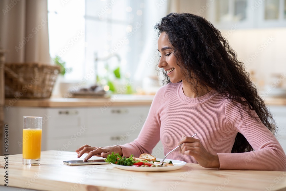 Smiling Millennial Lady Messaging On Smartphone In Kitchen While Having Tasty Breakfast Smiling Millennial Lady Messaging On Smartphone In Kitchen While Having Tasty Breakfast