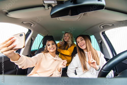 Group of funny women takes a selfie on the road driving a car. Best friends women having fun at vacation