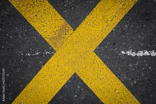 yellow lines on asphalt, Yellow crossing lines, like a x on a dark grey road, space for text, no person © YK