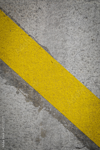 Grey asphalt with yellow stripe,  yellow marks on road, for background with space for text, abstract backdrop like race or transportation © YK