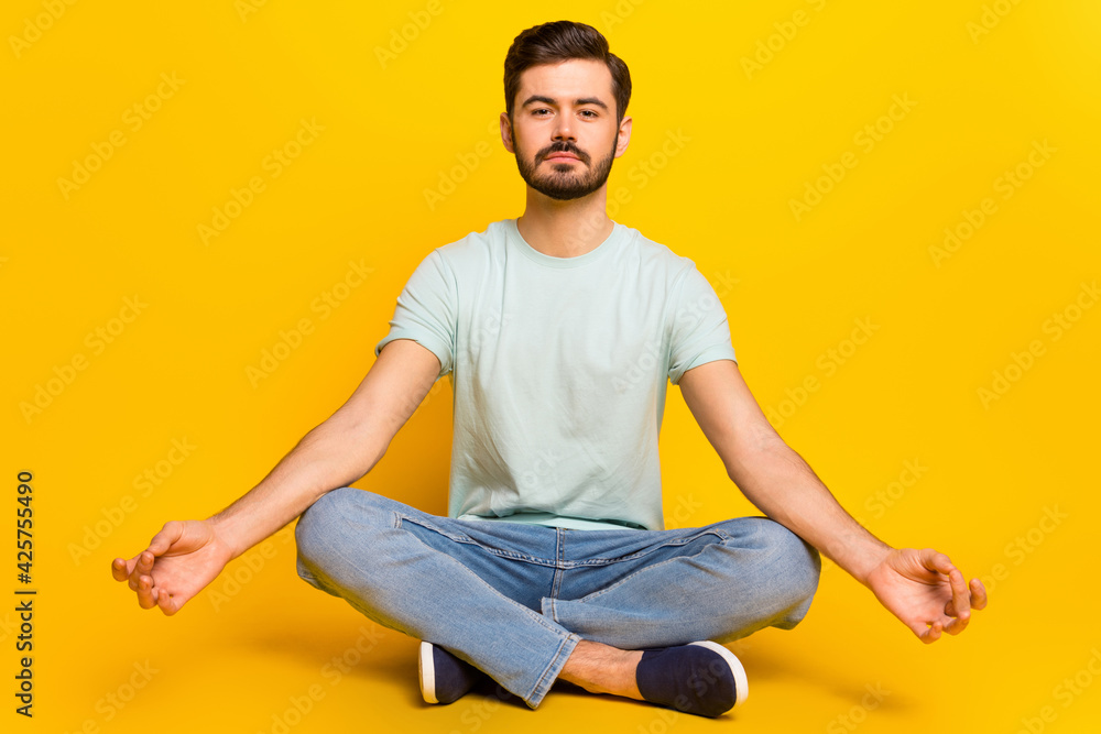 Portrait of attractive calm guy meditating spending free spare time isolated over bright yellow color background Portrait of attractive calm guy meditating spending free spare time isolated over bright yellow color background