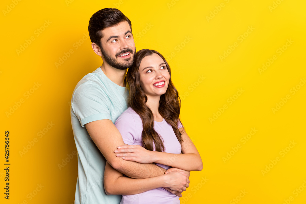 Portrait of attractive amorous cheerful couple embracing thinking copy space holiday isolated over bright yellow color background Portrait of attractive amorous cheerful couple embracing thinking copy space holiday isolated over bright yellow color background