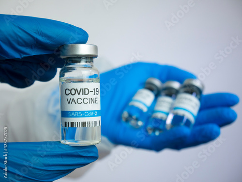 Hand with gloves holds COVID-19 vaccine, close up. Coronavirus vaccination concept.