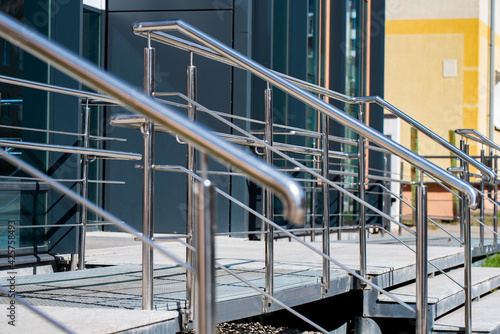 Silver chrome metal handrail on the background of wooden stairs during the day 