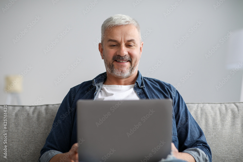 Closeup of relaxed senior man using laptop at home Closeup of relaxed senior man using laptop at home