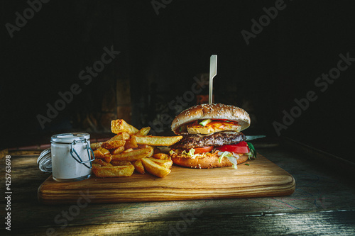 Tasty burger and french fries on wooden board