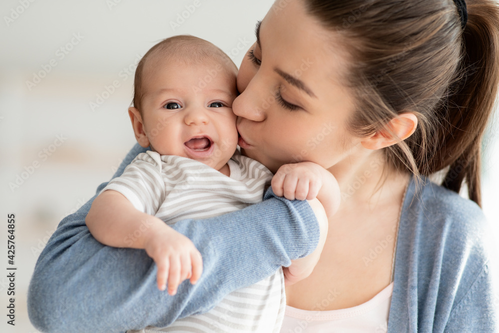 Mother's Love. Closeup Portrait Of Young Mom Kissing Her Cute Newborn Child Mother's Love. Closeup Portrait Of Young Mom Kissing Her Cute Newborn Child