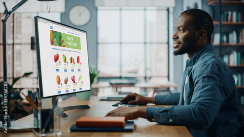 Wallpaper Mural Handsome Black African American is Using Desktop Computer with Groceries Delivery Web Page to Order Fresh Vegetables to Make Dinner. He Lives in Modern Huge Appatment. Torontodigital.ca