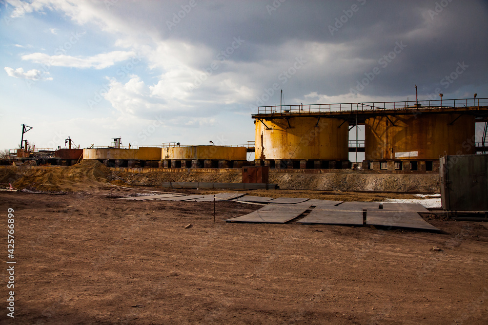 Fototapeta premium Demolition of outdated Soviet sulfuric acid plant.Old rusted yellow steel storage tanks for acid.