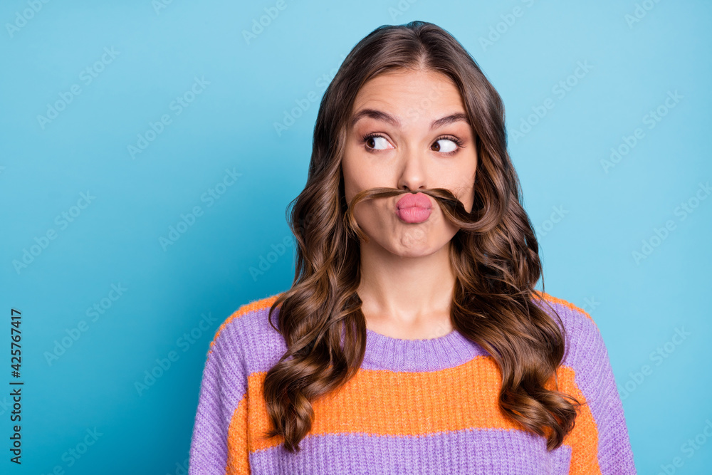 Fototapeta premium Portrait of attractive funny girl grimacing making fake mustache looking aside copy space isolated over bright blue color background
