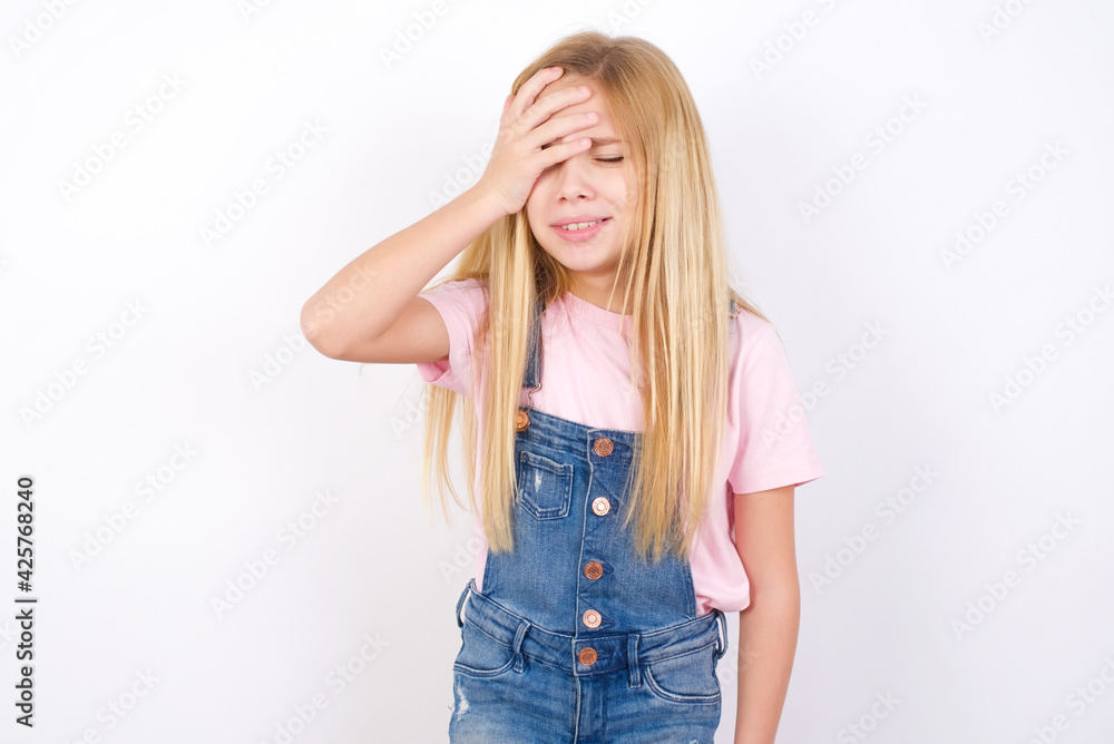 A very upset and lonely beautiful caucasian little girl wearing denim jeans overall over white background crying, A very upset and lonely beautiful caucasian little girl wearing denim jeans overall over white background crying,