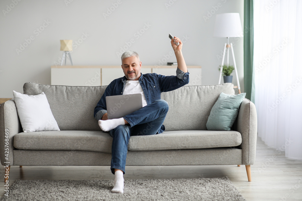 Relaxed senior man with laptop sitting on couch at home Relaxed senior man with laptop sitting on couch at home