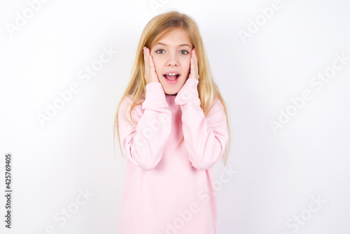 Beautiful caucasian blonde little girl wearing pink sweater Pleasant looking cheerful, Happy reaction