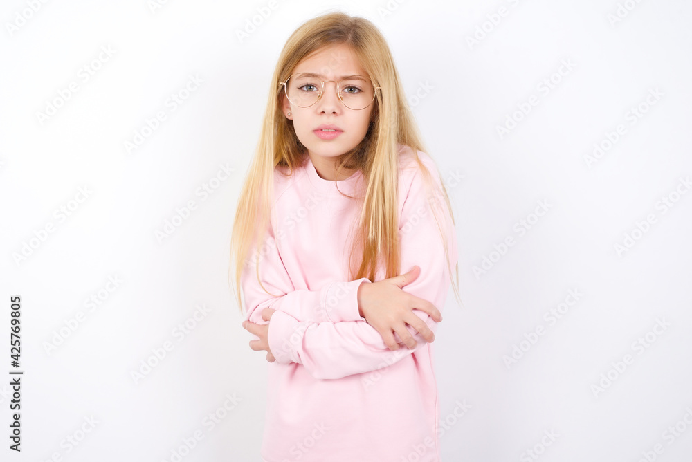 beautiful caucasian little girl wearing pink sweater shaking and freezing for winter cold with sad and shock expression on face. beautiful caucasian little girl wearing pink sweater shaking and freezing for winter cold with sad and shock expression on face.