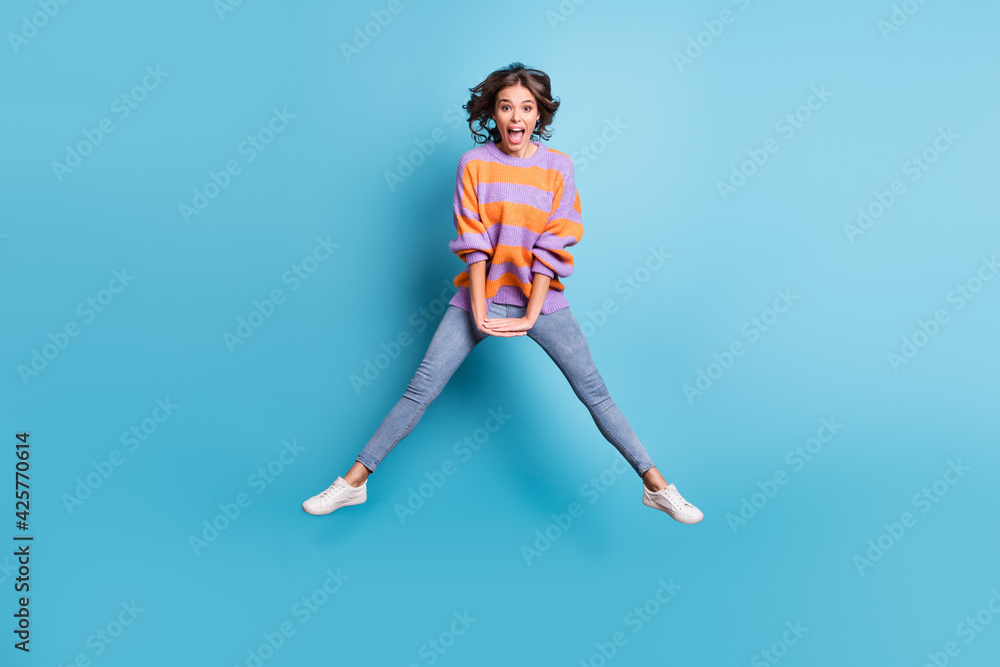 Full body photo of excited astonished young person jump high open mouth isolated on blue color background Full body photo of excited astonished young person jump high open mouth isolated on blue color background