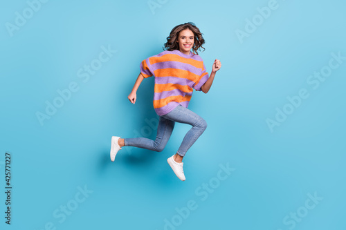 Full length body size view of charming active cheerful girl jumping running isolated over bright blue color background