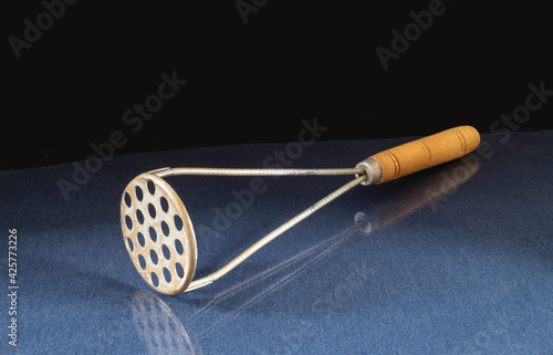 Bilde på lerret An old potato masher is lying on the table with a reflection