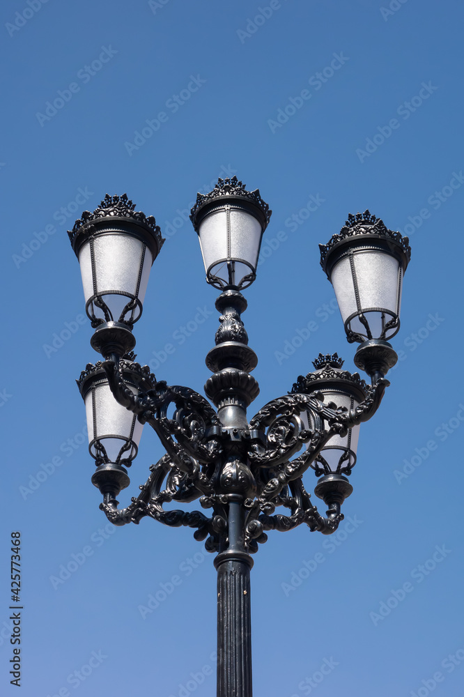 Vintage street light post against the blue sky. Old street lamp