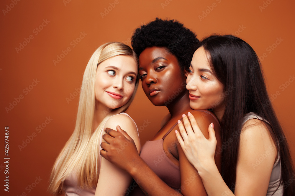 young pretty asian, caucasian, afro woman posing cheerful together on brown background, lifestyle diverse nationality people concept young pretty asian, caucasian, afro woman posing cheerful together on brown background, lifestyle diverse nationality people concept