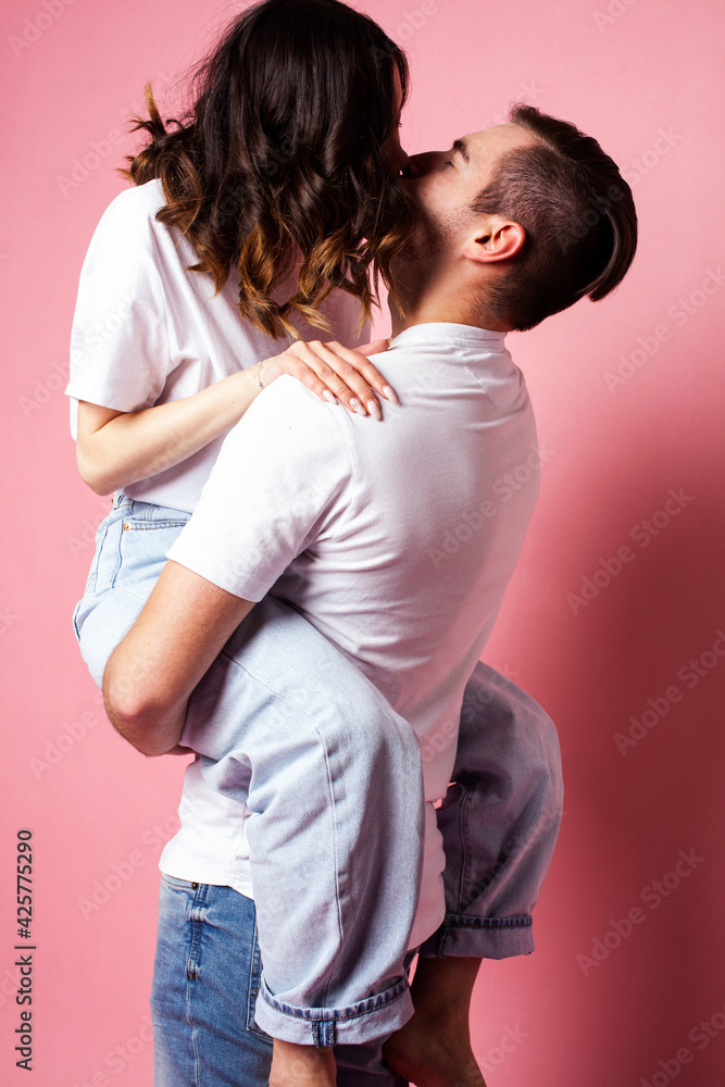 Naklejka premium young cheerful caucasian couple together having fun on pink background, guy ang girl modern relationship, lifestyle people concept