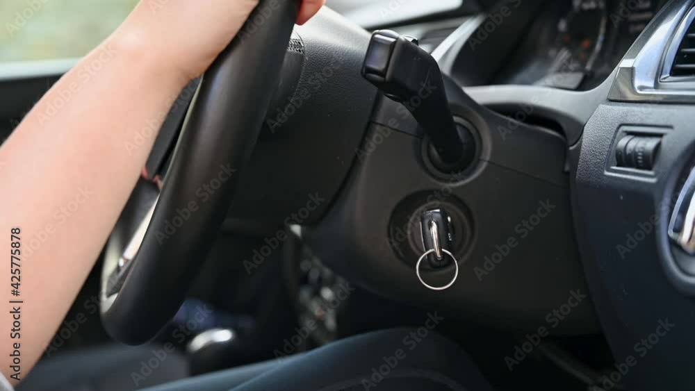 Close up as female hand inserts key into ignition and starts the car engine and then places hands on the steering wheel Close up as female hand inserts key into ignition and starts the car engine and then places hands on the steering wheel