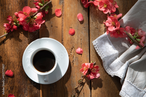 Italian spring breakfast: White coffee cup with italian espresso, pink spring flower and a embroidered cream cloth.