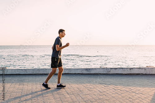 Young man jogging at the seafront early at the morning.