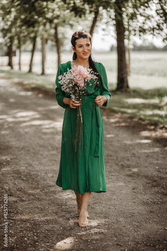 Young beautiful girl in the green dress posing with flower 