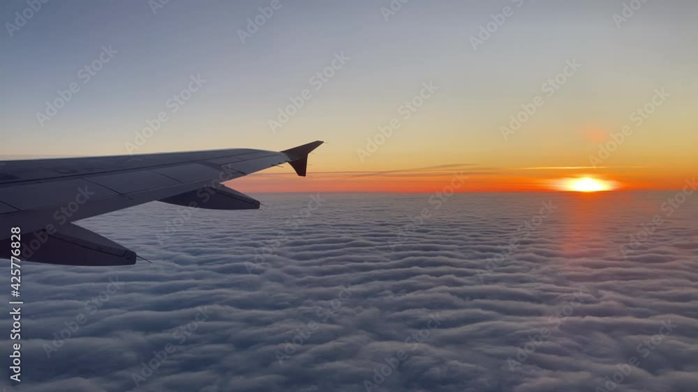 Up in the air, view of aircraft wing silhouette with dark blue sky horizon and cloud background in sun rise time, viewed from airplane window Up in the air, view of aircraft wing silhouette with dark blue sky horizon and cloud background in sun rise time, viewed from airplane window