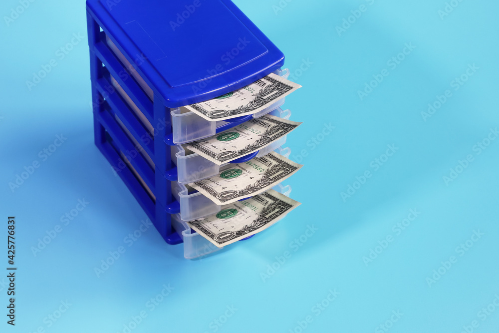 Box with open cells from which dollars are visible on blue background with copy space Box with open cells from which dollars are visible on blue background with copy space
