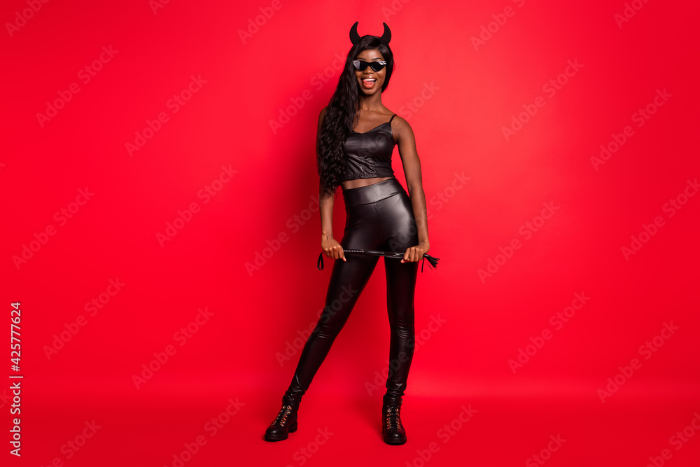 Full length body size view of attractive cheerful slim girl wear costume holding whip isolated over bright red color background Full length body size view of attractive cheerful slim girl wear costume holding whip isolated over bright red color background