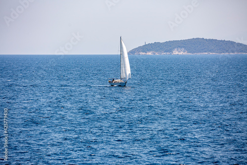 A single white sailing boat in the open sea.
