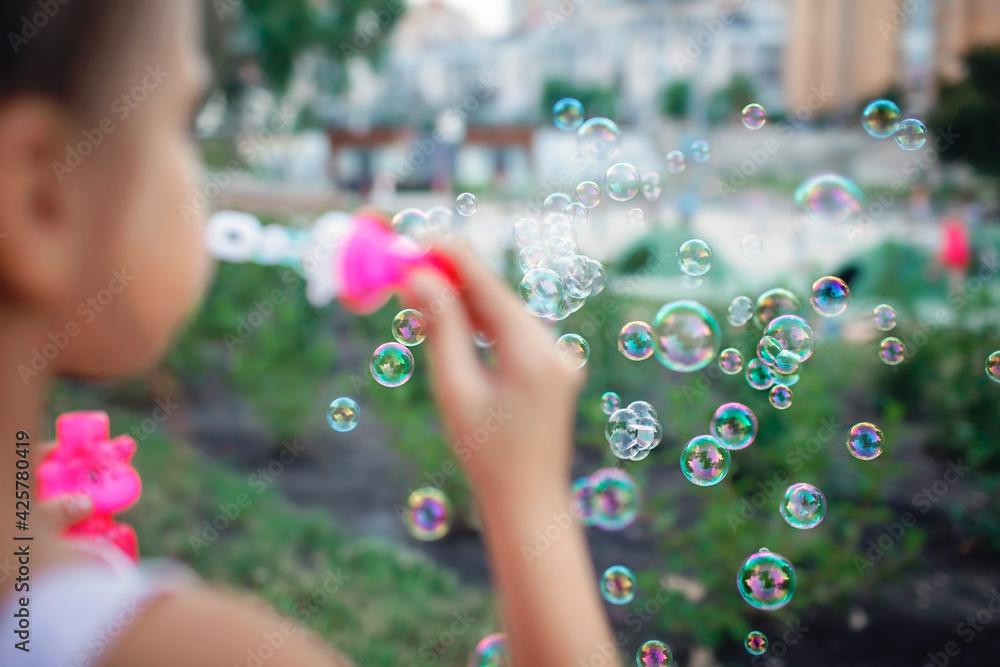 A little girl blowing soap bubbles in summer park, happy childhood, healthy outdoors lifestyle, light and airy, active weekend in the fresh air A little girl blowing soap bubbles in summer park, happy childhood, healthy outdoors lifestyle, light and airy, active weekend in the fresh air