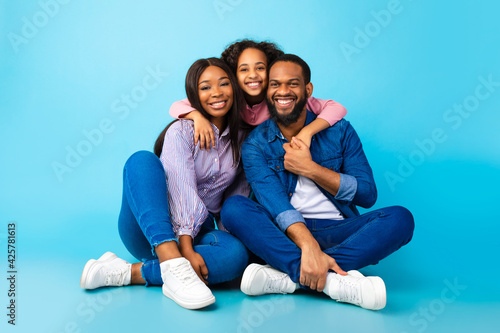 African American girl hugging her smiling mom and dad