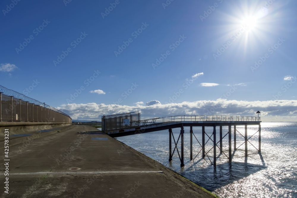 A walkway on the shore with a backlit jetty.