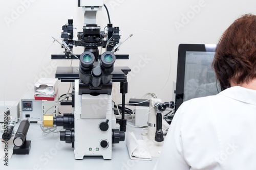 Doctor or scientist working with computer and microscope in biotech lab. Equipment in laboratory of Fertilization, IVF.