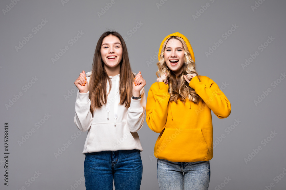 Two young women doing winner gesture celebrating isolated on gray background Two young women doing winner gesture celebrating isolated on gray background