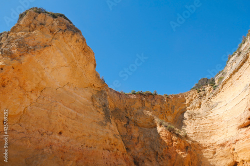 beautiful orange rock cliff in Algarve, Portugal against blue sky
