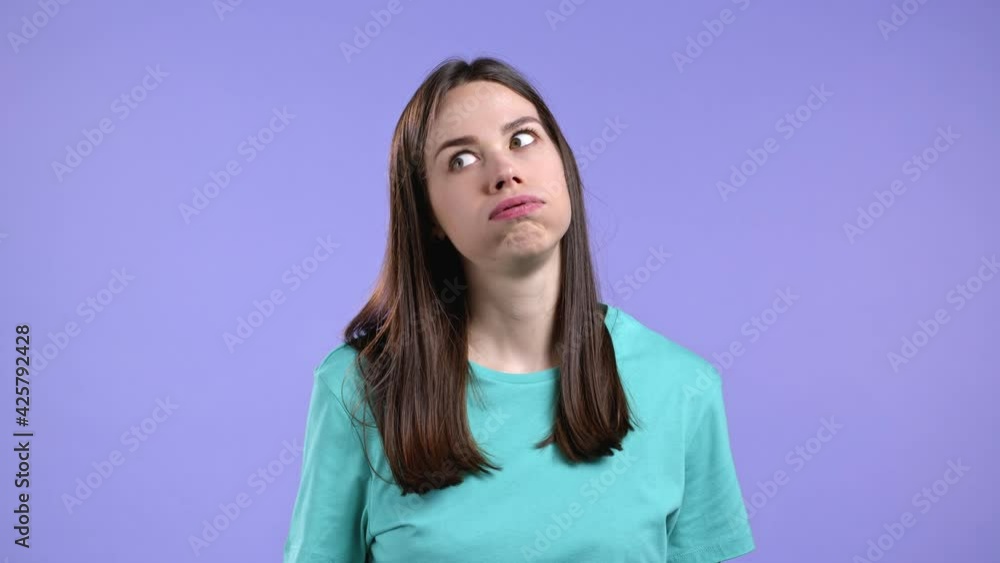 Portrait of girl, she exhales from heat or stuffiness. Heatstroke concept. Violet studio. Young tired woman is dissatisfied, unhappy. Portrait of girl, she exhales from heat or stuffiness. Heatstroke concept. Violet studio. Young tired woman is dissatisfied, unhappy.