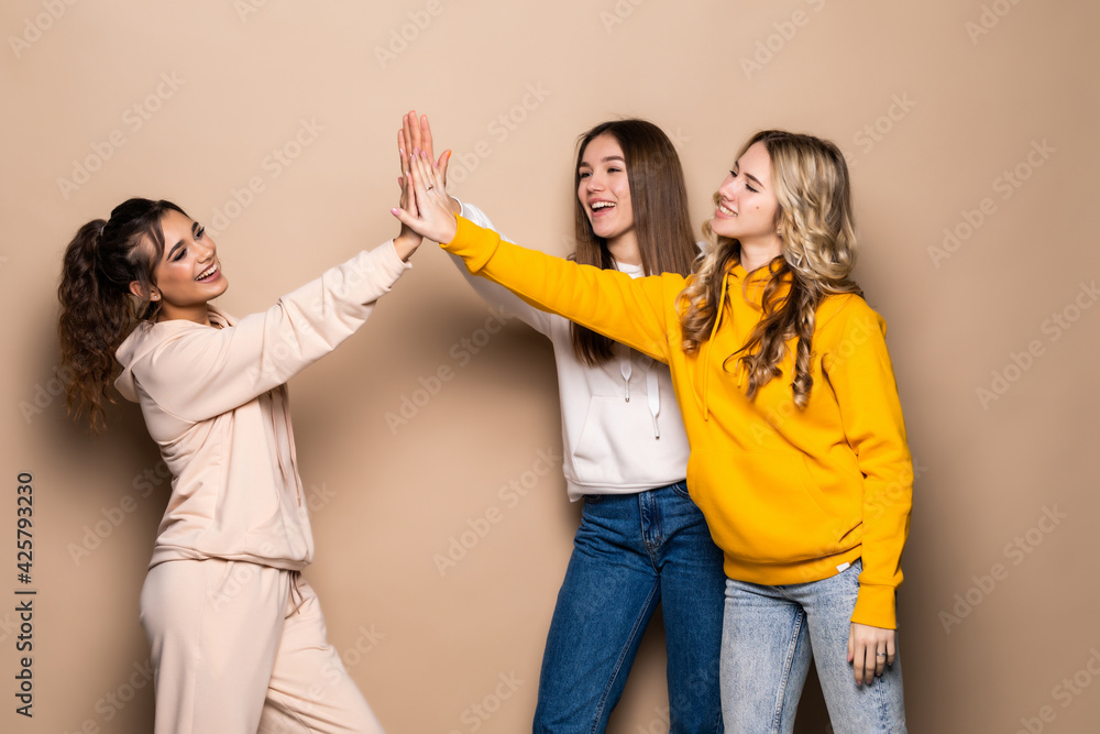 Obraz premium Beautiful three women friends give five isolated on beige background