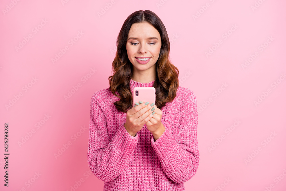 Portrait of attractive cheerful focused wavy-haired girl using device browsing isolated over pink pastel color background Portrait of attractive cheerful focused wavy-haired girl using device browsing isolated over pink pastel color background