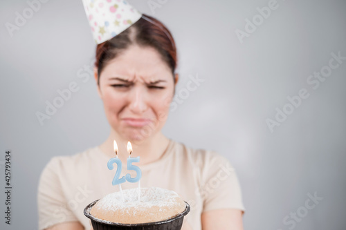 The unhappy woman is holding a cake with candles for her 25th birthday. The girl is crying on her anniversary. Copy space