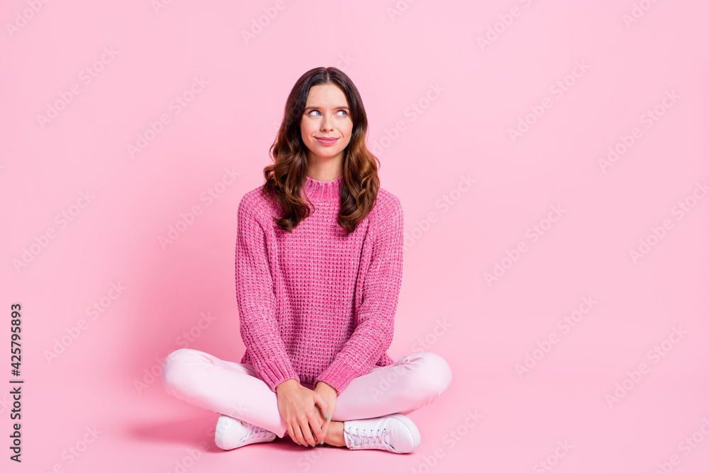 Full size photo of optimistic cool brunette lady sit look empty space wear pink sweater trousers sneakers isolated on pink background Full size photo of optimistic cool brunette lady sit look empty space wear pink sweater trousers sneakers isolated on pink background