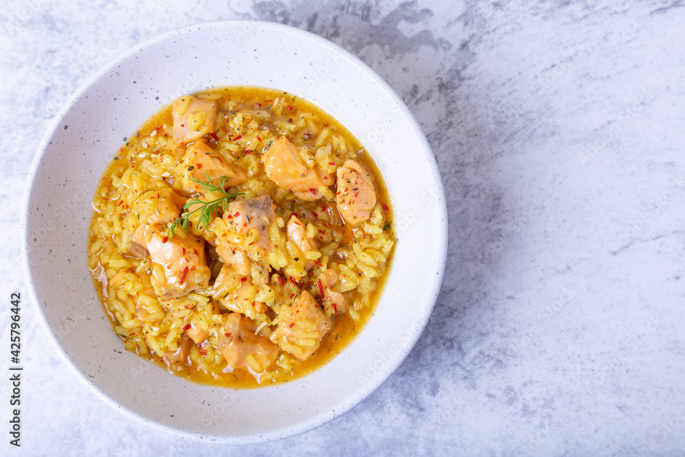 Risotto with salmon and saffron in a white plate. Traditional Italian cuisine. Close-up, top view. Risotto with salmon and saffron in a white plate. Traditional Italian cuisine. Close-up, top view.