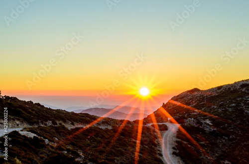 Beautiful Sunset over the Mountains of Crete Island, Greece. Panoramic View from a Mountain Top with a Dirt Road. Golden Sun Rays.