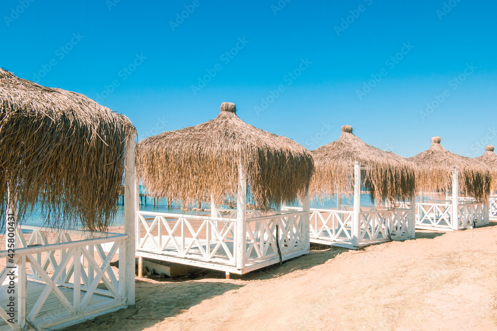 Massage huts with thatched roof on sand beach along seaside. Luxury vacation resort spa Massage huts with thatched roof on sand beach along seaside. Luxury vacation resort spa