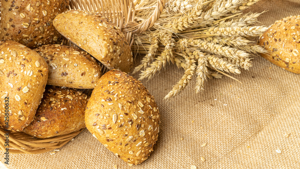Home baked bread. Rye bakery with crusty loaves and crumbs. Fresh rustic traditional bread with wheat grain ear or spike plant on natural cotton background. Design element for bakery product label. Home baked bread. Rye bakery with crusty loaves and crumbs. Fresh rustic traditional bread with wheat grain ear or spike plant on natural cotton background. Design element for bakery product label.